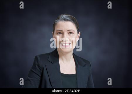 Freundlich lächelnde Frau mittleren Alters in einem schwarzen Blazer auf dunklem Hintergrund: professor, Anwalt, Anwalt oder Geschäftsfrau Stockfoto
