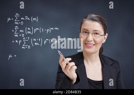Fernlernkonzept: Freundlicher Matheprofessor, Lehrer, Tutor oder persönlicher Coach vor der Tafel. Stockfoto