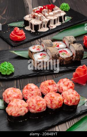 Sushi-Brötchen auf Brettern auf dunklem Holzhintergrund Stockfoto