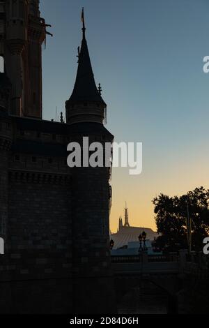 Space Mountain beleuchtet durch den Sonnenaufgang in der Ferne hinter den silhouetted Türmen des Cinderella Castle, Magic Kindom, Disney World Stockfoto