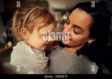 Glückliche Mutter hält Mädchen Kind in der Hand während der Wintersaison Zu Hause Stockfoto
