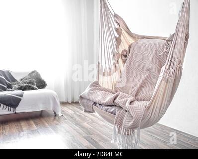 Hängemattenstuhl im Boho-Stil. Gemütliche Innenausstattung. Das Konzept der Ruhe und Komfort zu Hause. Leerzeichen für Text. Stockfoto