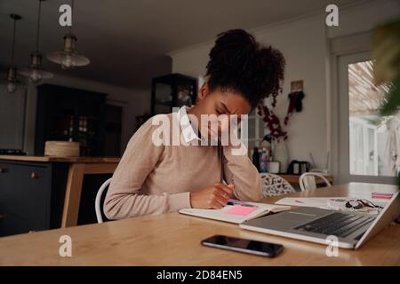 Junge Unternehmerin hält Hals wegen Schmerzen während der Arbeit Auf Laptop mit Tagebuch und Dokument zu Hause Stockfoto