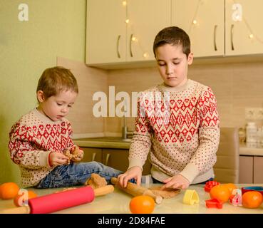 Fröhliche Jungen backen handgemachte festliche Lebkuchen. Weihnachtsplätzchen Stockfoto