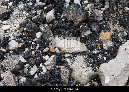 Zerbrochene Asphaltstücke auf einer Baustelle. Recycling und Wiederverwendung zerkleinerten Betonschutt, Asphalt, Baumaterial, Blöcke. Zerkleinert сoncrete Stockfoto