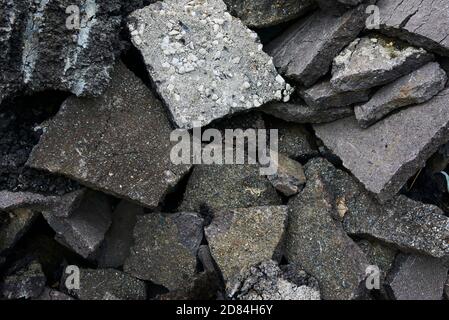 Zerbrochene Asphaltstücke auf einer Baustelle. Recycling und Wiederverwendung zerkleinerten Betonschutt, Asphalt, Baumaterial, Blöcke. Zerkleinert сoncrete Stockfoto