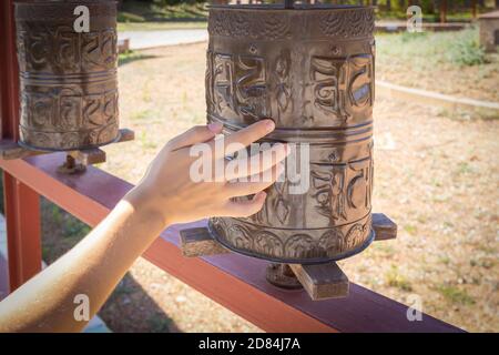 Junge weibliche Hand auf dem buddhistischen Gebetsrad in einem Tempel Stockfoto