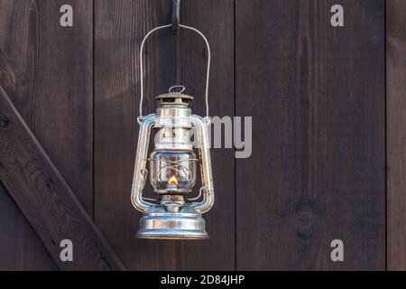 Altmodische Laterne mit Flamme an einer braunen Holzwand Stockfoto