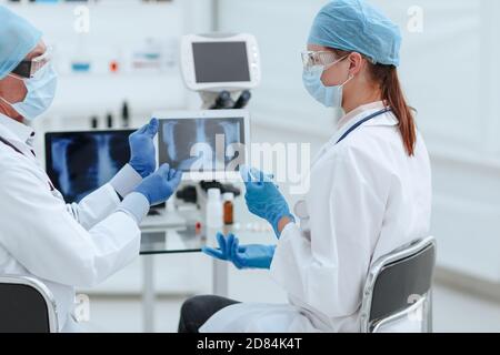 Medizinische Kollegen diskutieren über eine Röntgenaufnahme auf einem digitalen Tablet-Bildschirm. Stockfoto
