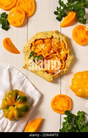 Torte mit gelben Tomaten, Paprika und Sesam, Galette mit Gemüse und Käse auf weißem Holzhintergrund, Draufsicht Stockfoto