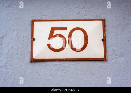 schild mit der Hausnummer 50 an der Steinmauer Stockfoto