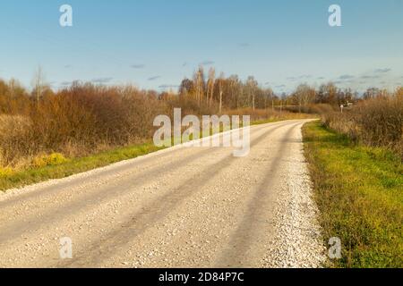 Die Herbstlandschaft mit teuren in ländlichen Gelände auf Hintergrund blauen Himmel. Straßenabdeckung Schotter Stockfoto