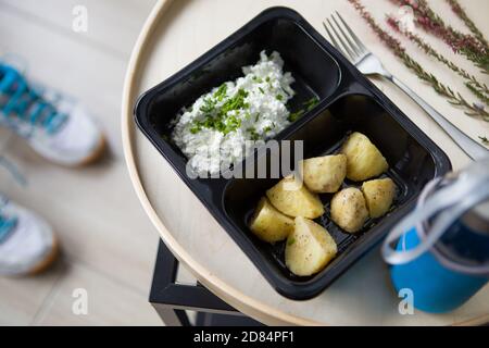 Catering-Essen mit einer gesunden, ausgewogenen Ernährung leckeres Mittagessen in einer Take-away-Box Lieferung verpackte Fertigmahlzeit in einem schwarzen Paket. Stockfoto