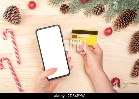 Weihnachten Online-Shopping-Konzept. Online-Shopping-Konzept mit Frau Hand mit Telefon und suchen Kreditkarte für Bestellung Produkt. winterurlaub Stockfoto