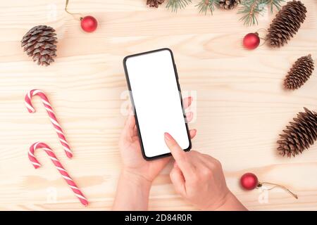 Weihnachten Online-Shopping. Weibliche Käufer macht Bestellung auf dem Bildschirm des Smartphones mit Kopieplatz. Frau kauft Geschenke für Heiligabend. Winterurlaub Verkäufe Stockfoto