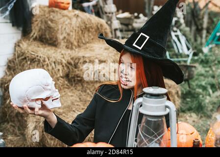 Ein Mädchen in einem Hexenkostüm mit Spaß an einem Halloween-Party auf der dekorierten Veranda Stockfoto