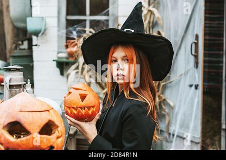 Ein Mädchen in einem Hexenkostüm mit Spaß an einem Halloween-Party auf der dekorierten Veranda Stockfoto