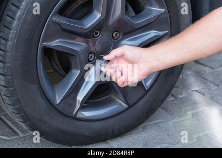 Konzept der Fahrzeugwartung. Сar Fahrer mit verschiedenen Reparaturwerkzeugen für die Installation von Kappen auf Schrauben auf Autorädern. Stockfoto