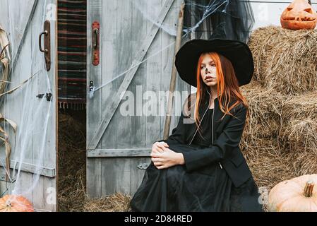 Ein Mädchen in einem Hexenkostüm mit Spaß an einem Halloween-Party auf der dekorierten Veranda Stockfoto