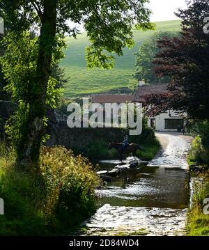 Die berühmte Malmsmead Bridge, umgeben von grünen Bäumen, mit der furt, die an der Brücke entlang läuft, Lorna Doone Country, Exmoor Stockfoto