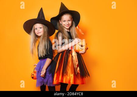 Lustige Kinder feiern Halloween auf orangefarbenem Hintergrund Stockfoto