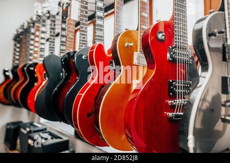 Nahaufnahme von vielen E-Gitarren in einer Reihe im Instrumentalgeschäft, Musikinstrument Konzept Stockfoto