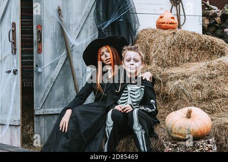 Kinder ein Junge in einem Skelett Kostüm und ein Mädchen In einem Hexenkostüm mit Spaß auf einer Halloween-Party Auf der dekorierten Veranda Stockfoto