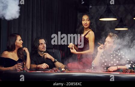 Gruppe von eleganten jungen Menschen, die Poker im Casino spielen Gemeinsam Stockfoto