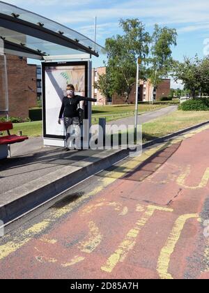 Poole, Dorset, Großbritannien. Juni 2020. Eine Frau, die eine Schutzmaske trägt, fährt während der Reisebeschränkungen in Covid an einer Bushaltestelle in den Bus. Stockfoto