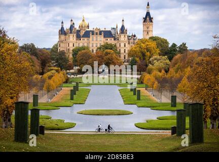 27. Oktober 2020, Mecklenburg-Vorpommern, Schwerin: Zwei Radfahrer sind auf dem Weg in den Park vor dem Schweriner Schloss, das bunt mit Herbstblättern ist. Foto: Jens Büttner/dpa-Zentralbild/dpa Stockfoto