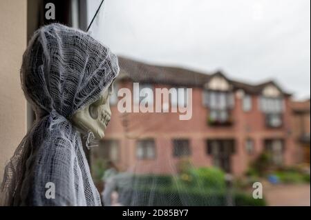 England, UK - 25 Oct 2020: Halloween Spielzeug aus dem Fenster durch seine eigene Reflexion und Blick einsam. Stockfoto