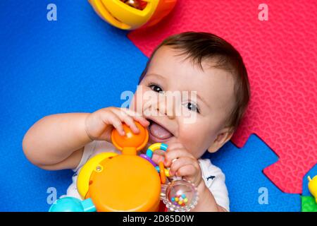 Lustige Baby spielen auf bunten eva Gummiboden. Kleinkind mit Spaß in seinem Haus. Draufsicht. Stockfoto