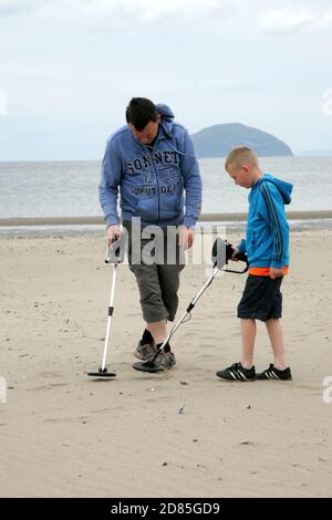 Girvan, Ayrshire, Schottland, Großbritannien. Eine Familie am Strand Metall entdeckt auf der Suche nach Schatz, im Hintergrund kann der ikonische Ailsa Craig gesehen werden Stockfoto