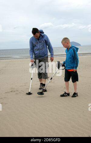 Girvan, Ayrshire, Schottland, Großbritannien. Eine Familie am Strand Metall entdeckt auf der Suche nach Schatz, im Hintergrund kann der ikonische Ailsa Craig gesehen werden Stockfoto