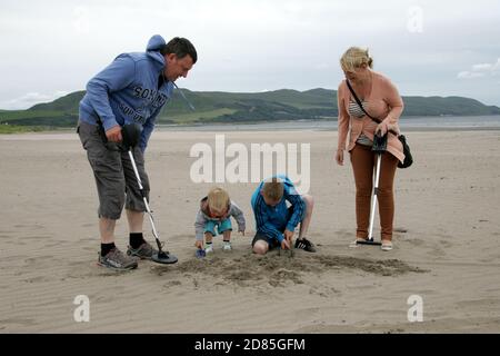 Girvan, Ayrshire, Schottland, Großbritannien. Eine Familie am Strand Metall entdeckt auf der Suche nach Schatz, im Hintergrund kann der ikonische Ailsa Craig gesehen werden Stockfoto