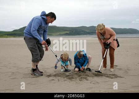 Girvan, Ayrshire, Schottland, Großbritannien. Eine Familie am Strand Metall entdeckt auf der Suche nach Schatz, im Hintergrund kann der ikonische Ailsa Craig gesehen werden Stockfoto