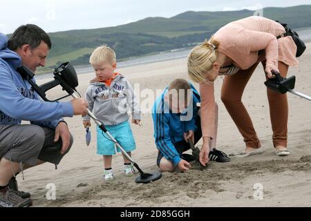 Girvan, Ayrshire, Schottland, Großbritannien. Eine Familie am Strand Metall entdeckt auf der Suche nach Schatz, im Hintergrund kann der ikonische Ailsa Craig gesehen werden Stockfoto