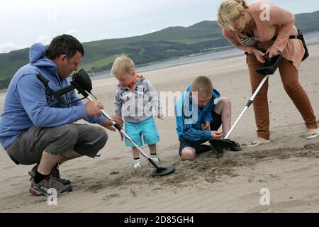 Girvan, Ayrshire, Schottland, Großbritannien. Eine Familie am Strand Metall entdeckt auf der Suche nach Schatz, im Hintergrund kann der ikonische Ailsa Craig gesehen werden Stockfoto