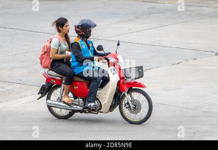 SAMUT PRAKAN, THAILAND, JULI 25 2020, EIN Taxifahrer auf einem Motorrad fährt mit einer Frau. Der mototaxi-Fahrer trägt einen Passagier. Stockfoto