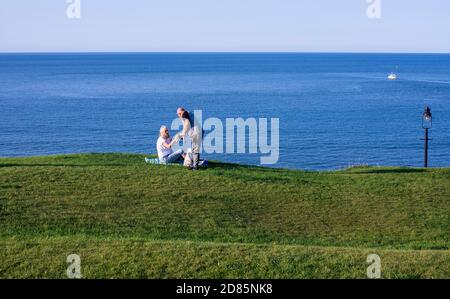 Paar auf Gras auf See, Whitby, England, Großbritannien Stockfoto