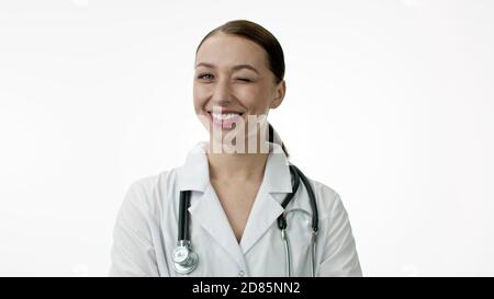 Die Ärztin lächelt breit mit einem schneeweißen Lächeln und zwinkert. Isoliert Stockfoto