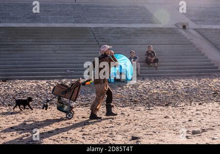 Frau mit Hund und Haustier Kinderwagen am Strand, Whitby, England, Großbritannien Stockfoto