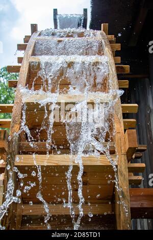 Das Mühlrad dreht sich unter einem Wasserstrahl, aus nächster Nähe. Stockfoto