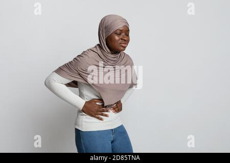 Magenschmerzen. Kranke afrikanische muslimische Frau im Hijab, die an Bauchschmerzen leidet Stockfoto