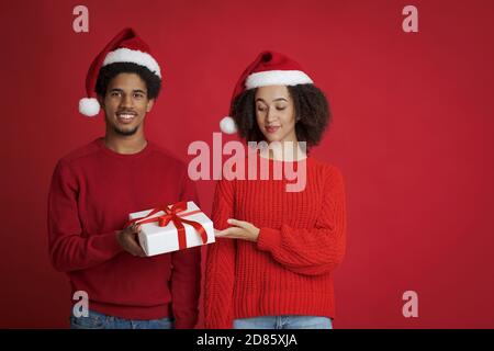 Winterferien Feier. Junger afroamerikanischer lächelnder Mann, der Weihnachtsgeschenk anbietet Stockfoto