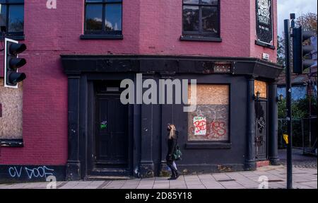 Frau, die an einem vernagelten Pub vorbeigeht, Norwich, Norfolk, Großbritannien Stockfoto