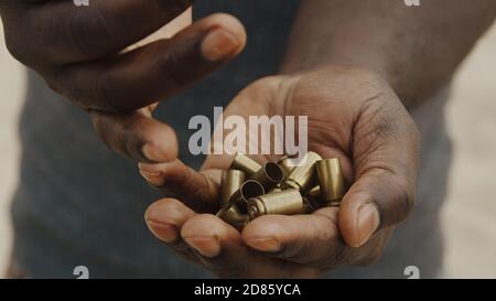 Nahaufnahme, schwarze Mann Hände Zählen gebrauchte Kugeln. Viele Bullet-Fälle wurden von einer Hand zur anderen übertragen. Hochwertige Fotos Stockfoto