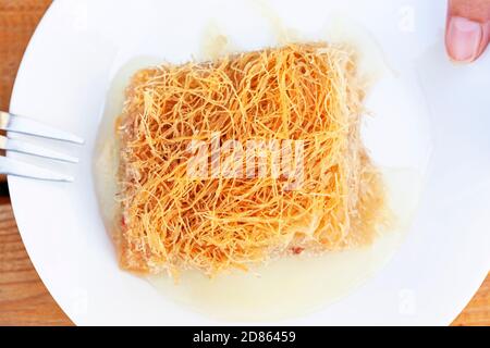 Kadaif Dessert auf Teller aus Honig Draufsicht gemacht. Köstliche knusprige Backwaren aus dem Nahen Osten. Stockfoto