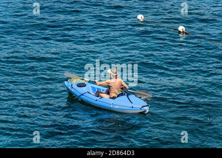 Reife Frau an Bord eines blauen Kajaks, paddeln im blauen Mittelmeer, Golf von La Spezia, Ligurien, Italien, Europa. Stockfoto