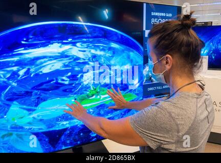 Frau trägt Gesichtsmaske Blick auf Samsung High Definition QLED 8K Q850T Fernseher, TV-Bildschirm im Geschäft.